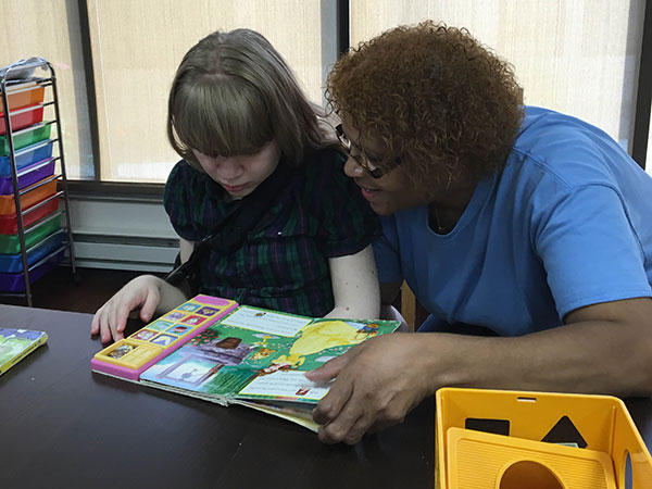 Woman teaching a little girl how to read