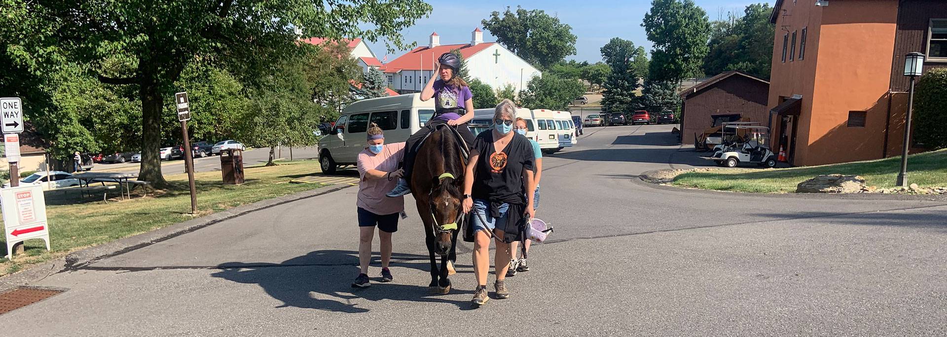 Three assistants walking next to a verland resident ridding a horse